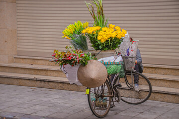 Fototapeta na wymiar A street vendor selling flowers on a bicycle in Hanoi, Vietnam