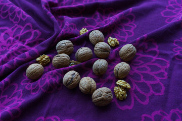 There are walnut and walnut kernels on the tablecloth. Some of the walnuts are selective focus....