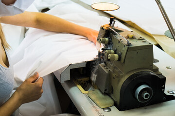 Woman hands with fabric at sewing machine