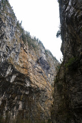 View from below of a mountain gorge with high cliffs and clouds, cloudy autumn day