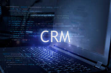 Fototapeta premium CRM inscription against laptop and code background. Customer relationship management system.
