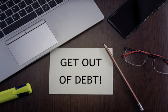 Get out of debt card. Top view of office table desktop background with laptop, phone, glasses and pencil with card with inscription get out of debt. Business concept.