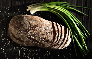 A Large Loaf Of Bread With Green Onions Black Background.