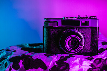 Vintage camera in vibrant bold purple and blue holographic colors. Concept art. Minimal summer surrealism.

