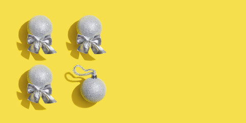 Creative pattern with silver New years balls, holiday toys on yellow. Christmas greeting card.  Minimal style trend color illuminating yellow and ultimate gray.