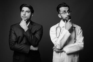 Studio shot of young handsome Iranian brothers together shot in black and white