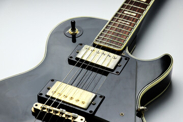 Black and gold colored electric guitar on a white background - close up