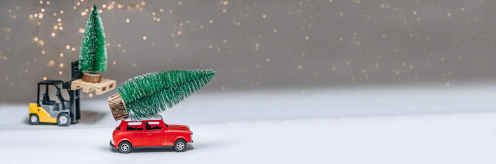 banner, loader and a red retro manina are carrying green trees. Against the background of festive lights. Concept on the theme of Christmas and New Year.