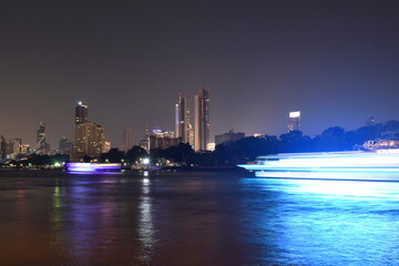 Fototapeta na wymiar blurry ship floating with building near river in night of Bangkok Thailand