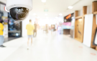 Modern public CCTV camera with blur interior shopping mall background. Recording cameras for monitoring all day and night. Concept of surveillance and monitoring with copy space.