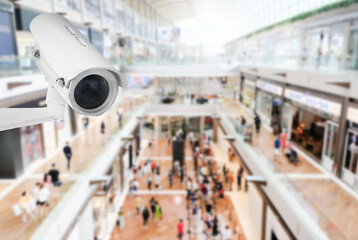 Obraz premium Modern public CCTV camera with blur interior shopping mall background. Recording cameras for monitoring all day and night. Concept of surveillance and monitoring with copy space.