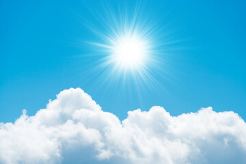 Beautiful fluffy white clouds on bright blue sky and shining sun with sun rays