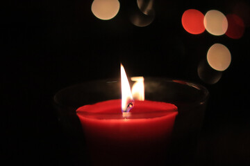 red candle flame at night with lights in background