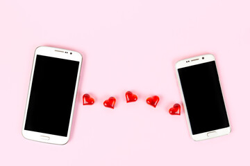 Mobile phones with black screen and red hearts isolated on pink pastel background. Top view, flat lay, copy space. Valentines day, love, technology, online dating concept.