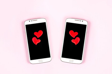 Mobile phones with black screen and red hearts isolated on pink pastel background. Top view, flat...