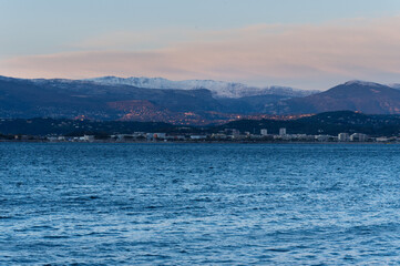 Snow on the mountains and the Mediterranean sea. Far away the lights from Grasse, France.