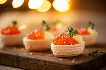 red salted salmon caviar in waffle tartlets on a wooden board