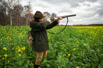 Treibjagd, junge J&auml;gerin zielt auf fl&uuml;chtiges Wild - jagdliches Symbolfoto.