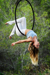 Portrait of young woman doing back balance on the aerial hoop in the park. © chok1234567