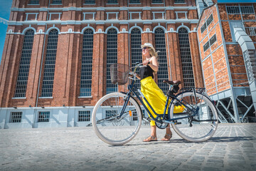 Obraz premium Happy traveler woman with her bicycle rides in city 
