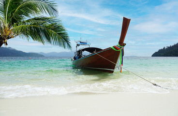 Fototapeta na wymiar A boat that leads tourists to a white beach Near the coconut tree