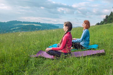 Mother and daughter doing yoga in nature, fresh air in the park