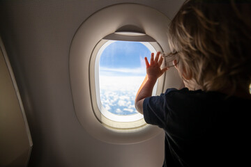 cute toddler points his finger at the sky through the window. first flight concept, traveling with children. - obrazy, fototapety, plakaty