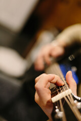 Playing acoustic guitar. The guy is playing chords on the guitar. Black guitar, fingers. Evening...
