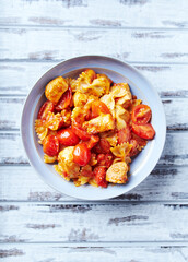 Farfalle pasta with chicken breast, cherry tomatoes and fresh basil. Bright wooden background. Top view.	