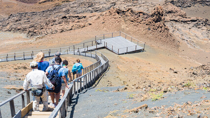 Group of tourists walking on a gangway, descending a slope in Bartolomè island, Galapagos...