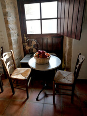 Detail of a small sitting room with two wooden chairs and table with a basket of pomegranates, Monemvasia, Greece