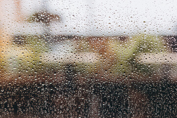 nostalgic mood: gloomy blurred cityscape in rainy weather outside the window with raindrops. selective focus, copy space