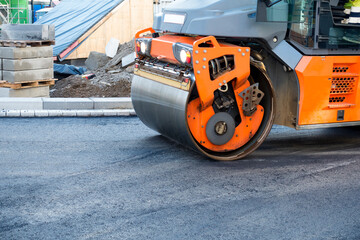 Modern heavy asphalt roller that stack and press hot asphalt. Yellow road repair machine. Repairing in modern city with vibration roller compactor