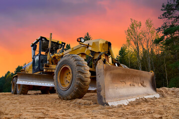 Motor Grader on road construction in forest area. Greyder leveling the sand, ground and gravel...