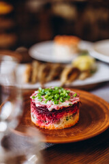 traditional russian herring salad under a fur coat and olives on a wooden table next to other festive dishes