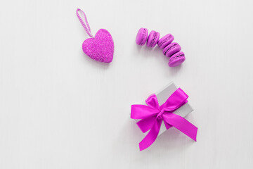 Purple macaroons, heart and gift box on a white wooden painted background. Valentine's Day. Top view.