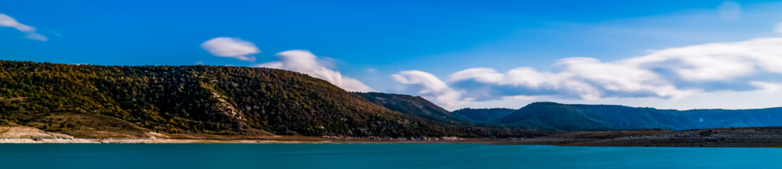 Long exposure cotton clouds on the blue sky. Lake and rural landscape. Panoramic shot. High resolution sharp photo. Panorama banner.