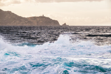 Stormy Mediterranean sea with Revellata and lighthouse in distance
