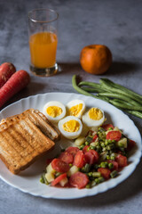 Close up of healthy food items bread slices, boiled vegetables and eggs in a plate along with condiments.