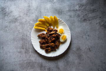Continental delicacy chicken wings on a plate along with potato wedges.