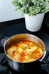 Soup with poultry, potatoes and greenery. a pot of soup on a black stove