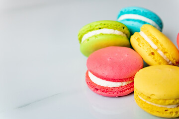 multicolored macaroon cookies lie on a white kitchen table