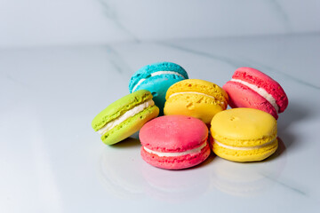 multicolored macaroon cookies lie on a white kitchen table