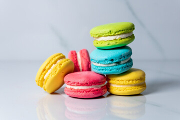 multicolored macaroon cookies lie on a white kitchen table