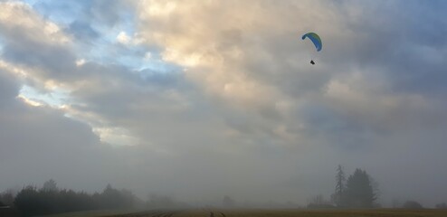 Paraglider on a misty day over a dramatic sky