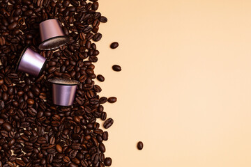 Disposable coffee capsules over coffee beans background with copy space. Morning dose of caffeine, energy, flavor concept