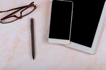 Minimal work space desk. gadgets with digital tablet and smartphone, glasses, pen in the marble table