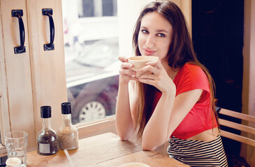 Beautiful young woman with a cup of tea at a cafe 