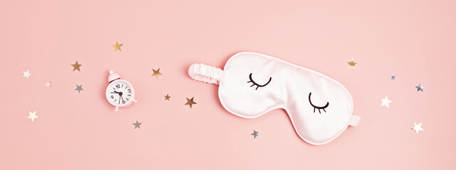 Sleeping mask and classic alarm clock on pink pastel background.  Minimal concept of rest, quality...
