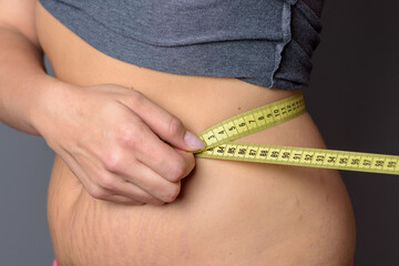 Young blond woman measuring her waist